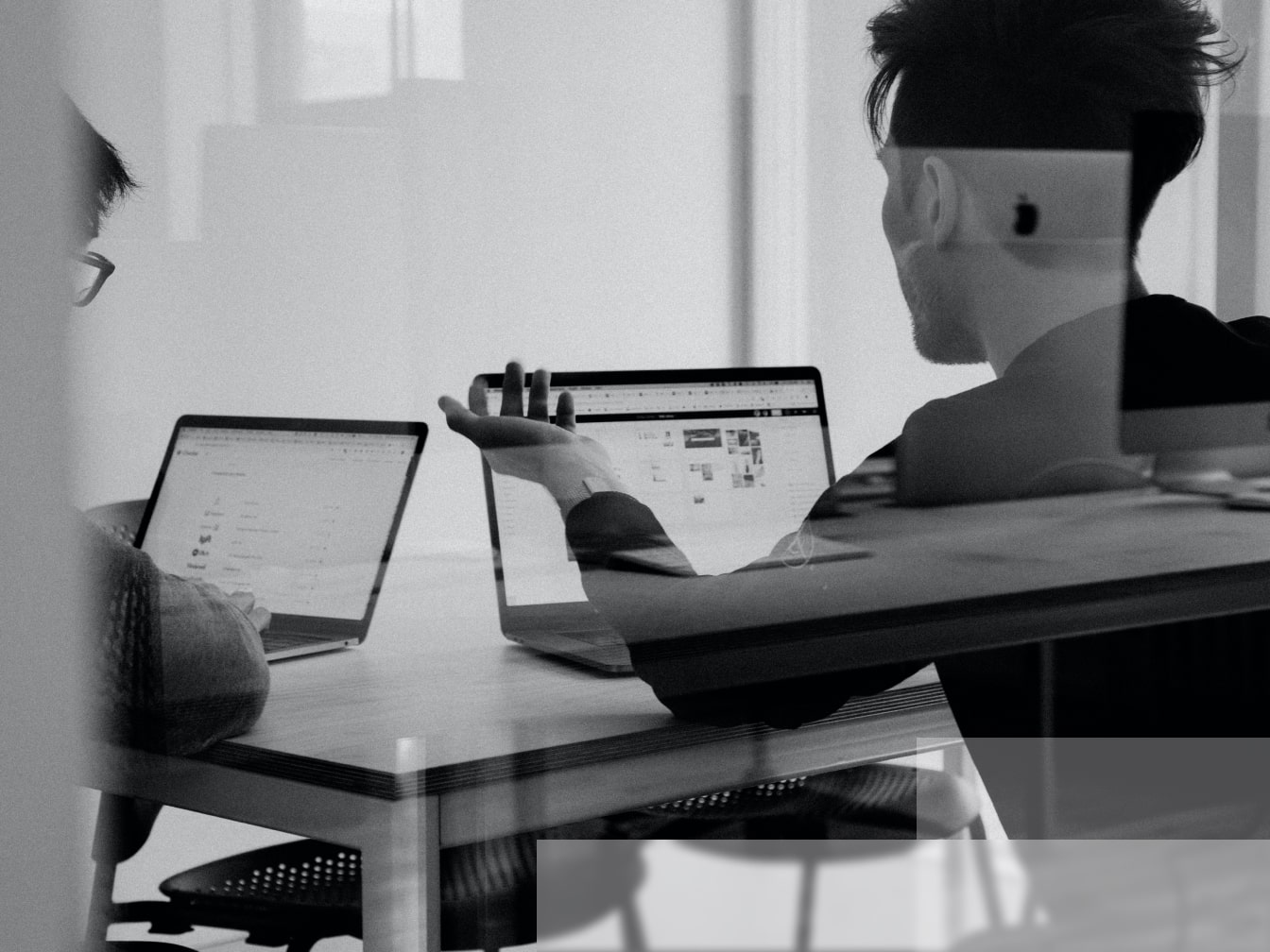 two people sitting at a table with laptops