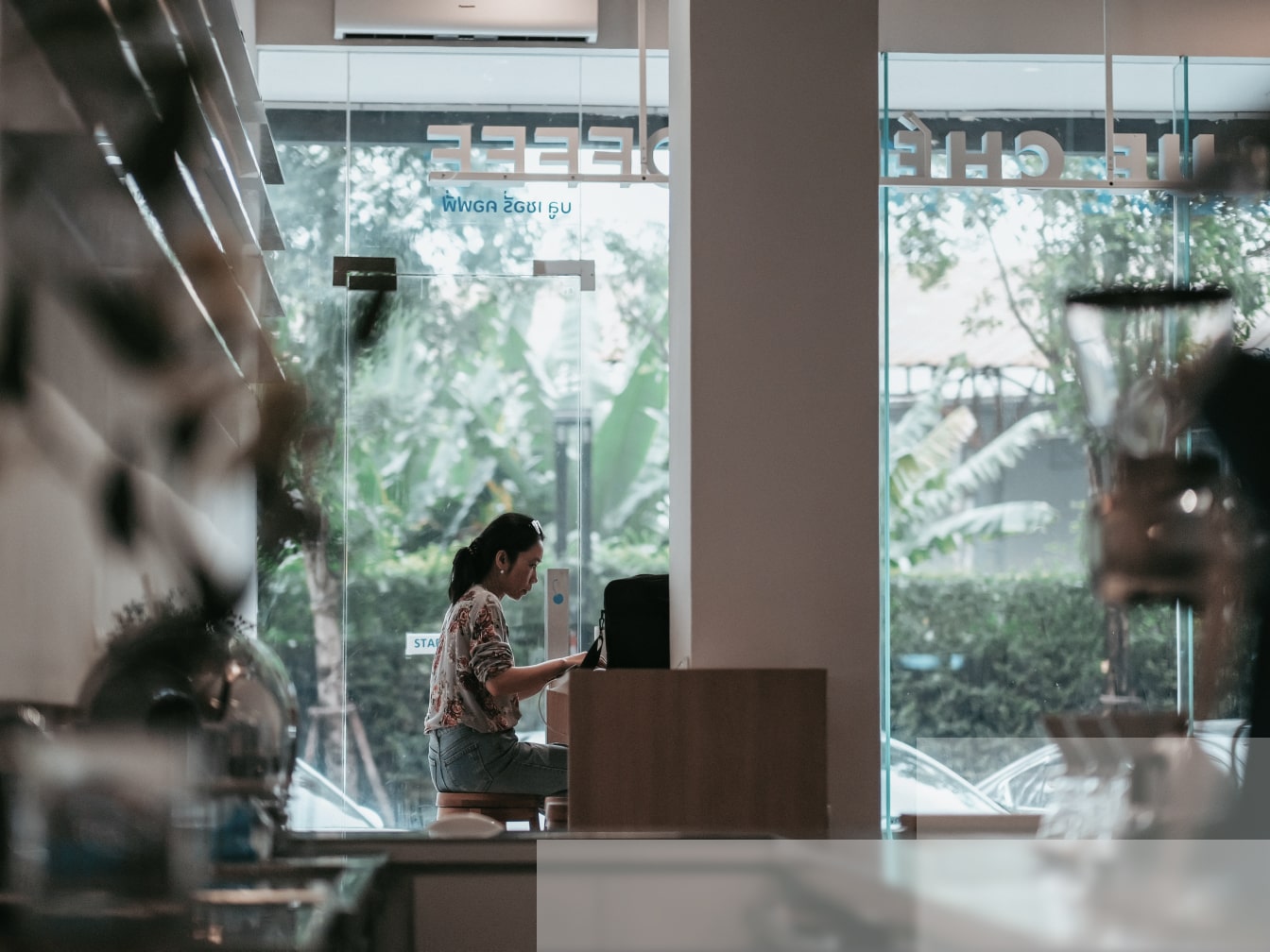 a woman standing in front of a window looking at her cell phone.