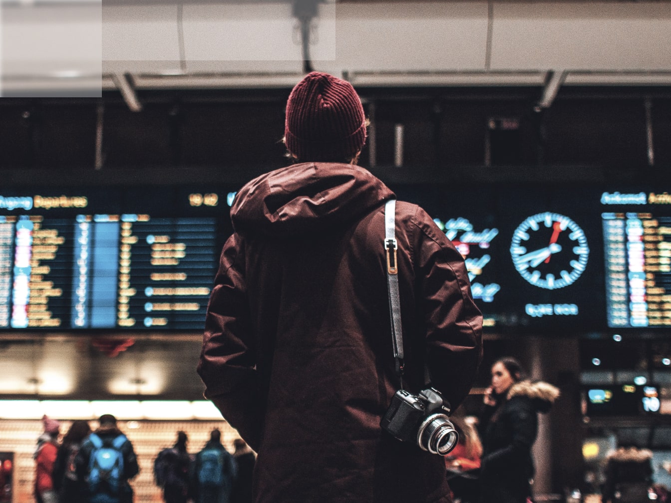 a person with a camera standing in front of  airport table schedule.