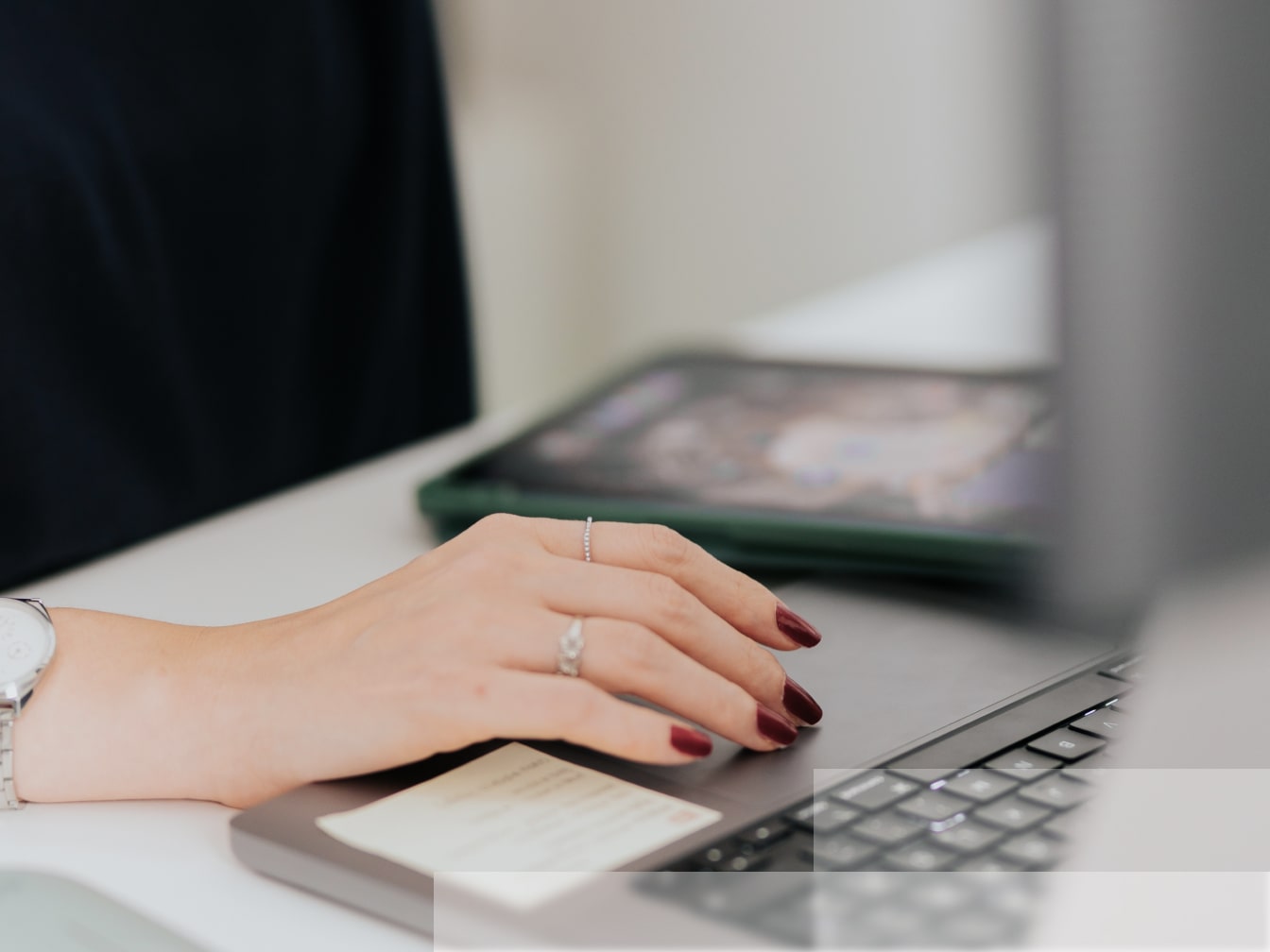 a woman's hand on a laptop next to a cell phone.