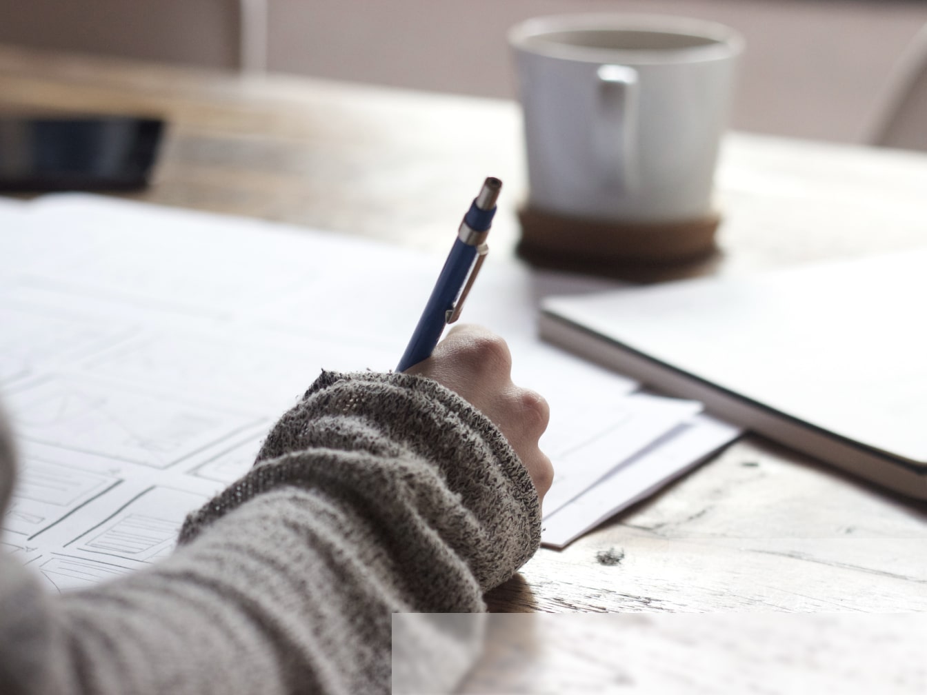 a person writing on a piece of paper with a pen.